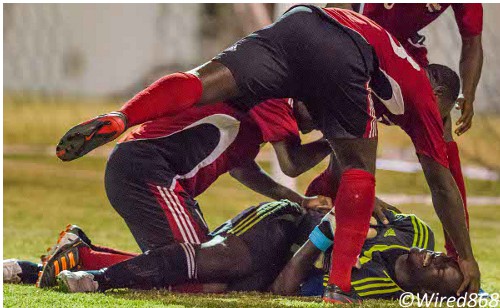 Photo: Trinidad and Tobago national goalkeeper Jan-Michael Williams (bottom) is congratulated by teammates after inspiring the squad to the 2012 Caribbean Cup final. (Courtesy Allan V. Crane/Wired868)
