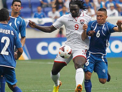 Photo: Trinidad and Tobago forward Kenwyne Jones holds off El Salvador midfielder Richard Menjivar (far right). (Courtesy FoxSoccer)